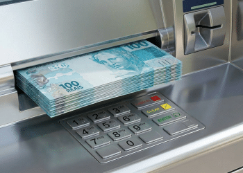 Caixa eletrônico prateado libera maço de cédulas de cem reais durante saque do abono salarial