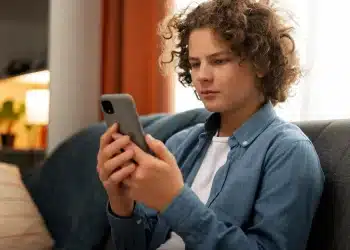 Jovem utilizando celular para acessar plataforma de apoio emocional online.