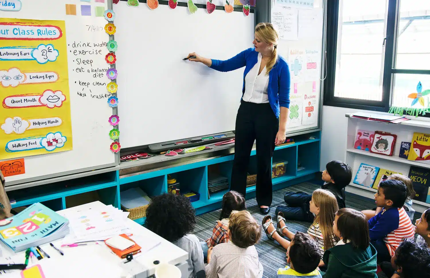 Professora ministra aula para crianças em uma sala de ensino, representando a aplicação da Prova Nacional Docente 2026.