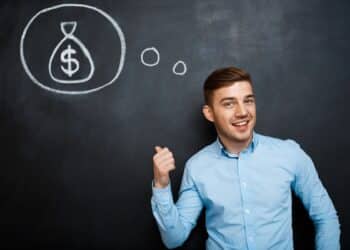 Homem jovem em camisa azul claro sorri e aponta para desenho de saco de dinheiro no quadro-negro, simbolizando as profissões mais bem pagas de 2026.