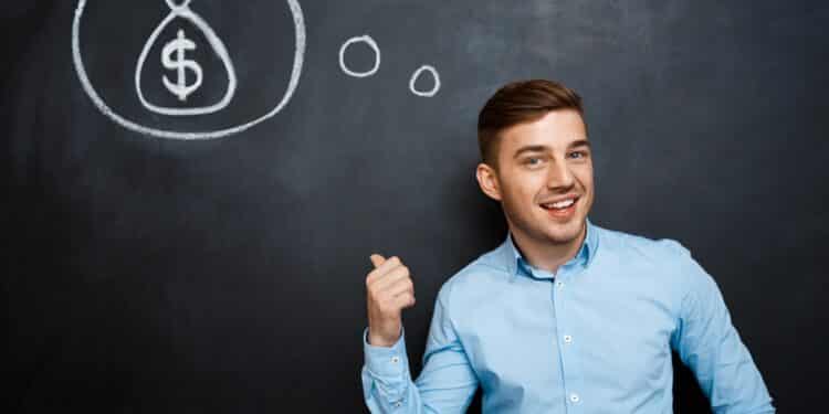 Homem jovem em camisa azul claro sorri e aponta para desenho de saco de dinheiro no quadro-negro, simbolizando as profissões mais bem pagas de 2026.