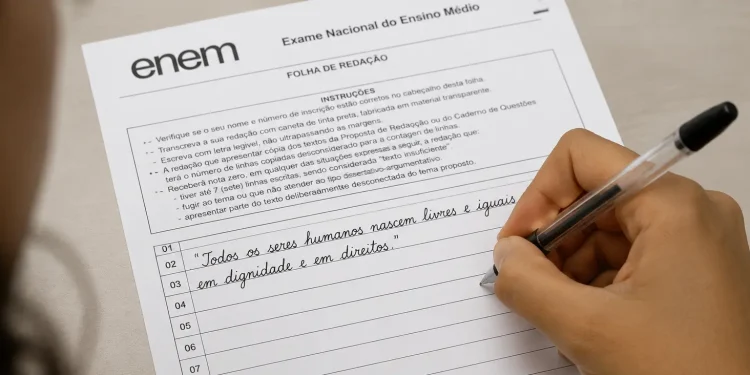 Estudante escrevendo redação do Enem em folha oficial com caneta preta.