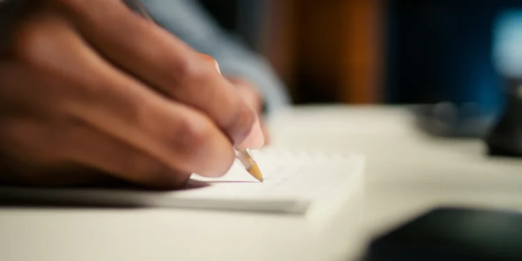 Estudante escreve redação do Enem em folha de papel durante preparação para alcançar nota 1000 na prova.