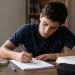 Estudante escrevendo uma redação do Enem com livros e materiais de estudo sobre a mesa, simbolizando as melhores dicas para escrever uma redação do Enem.