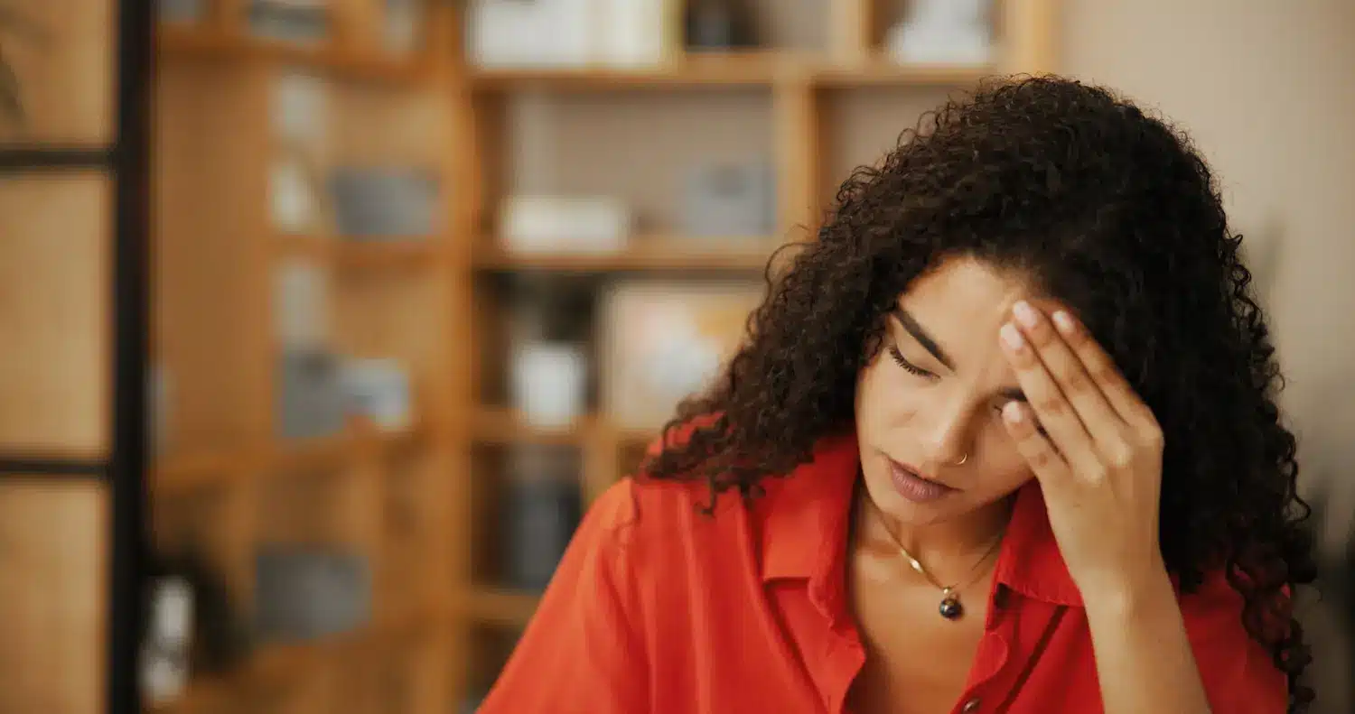 Mulher em ambiente de trabalho demonstrando cansaço e estresse ao lidar com sobrecarga mental e responsabilidades acumuladas.