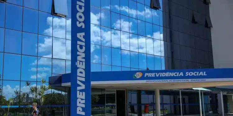 Fachada do edifício da Previdência Social (INSS) com reflexo do céu em vidro espelhado, simbolizando melhora no atendimento.