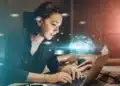 Estudante utilizando notebook em ambiente de estudo com elementos digitais que representam o uso de inteligência artificial em vestibular online.