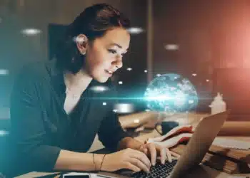 Estudante utilizando notebook em ambiente de estudo com elementos digitais que representam o uso de inteligência artificial em vestibular online.