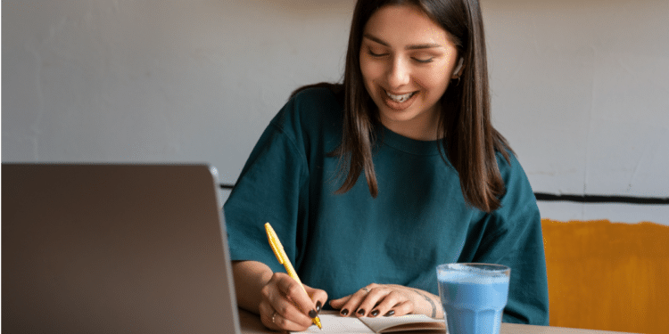 Jovem sorrindo estuda em casa com notebook.