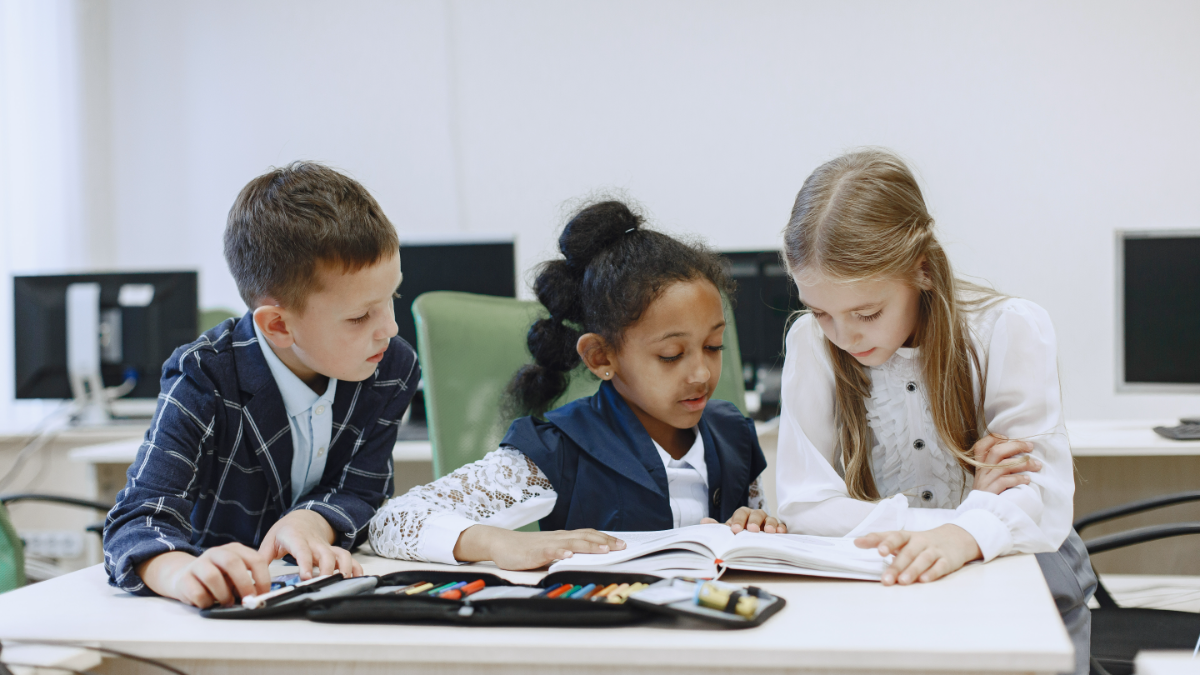 Crianças estudando juntas em sala de informática escolar.