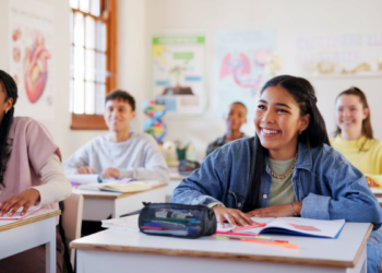 Estudantes atentos em aula de ciências em ambiente escolar descontraído.