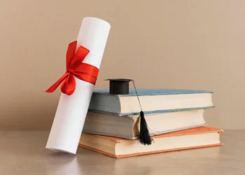 Imagem ilustrativa sobre o certificado do Encceja ao lado de livros e capelo de formatura.