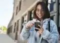 Estudante acessa aplicativo no celular, representando o uso do Clique Escola para consulta de informações educacionais.
