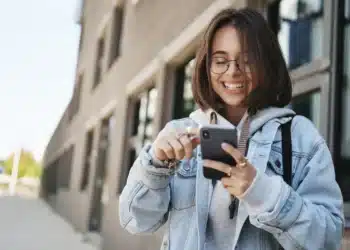 Estudante acessa aplicativo no celular, representando o uso do Clique Escola para consulta de informações educacionais.