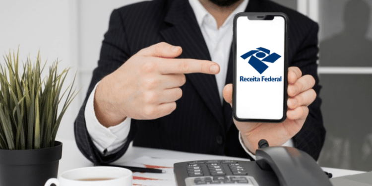 Homem de terno apontando para celular com a logo da Receita Federal.