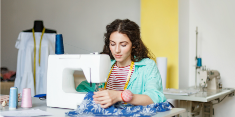 Jovem costureira trabalhando em ateliê moderno com máquina de costura.