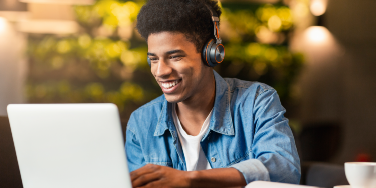 Jovem estuda online com fones de ouvido e notebook em ambiente aconchegante.