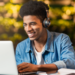 Jovem estuda online com fones de ouvido e notebook em ambiente aconchegante.
