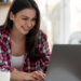 Jovem sorridente mexendo em notebook em casa.