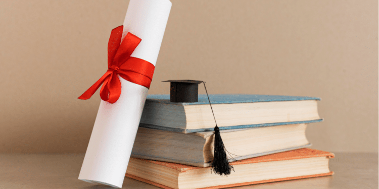 Diploma de formatura com fita vermelha ao lado de livros e capelo acadêmico.