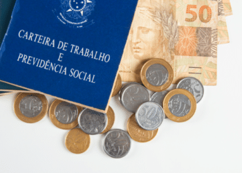Carteira de Trabalho ao lado de reais representa vínculos e direitos.