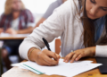 Estudante concentrada realizando prova em sala de aula.