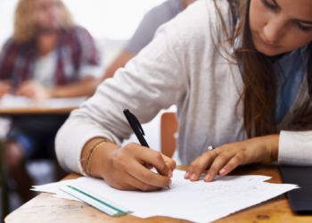 Estudante concentrada realizando prova em sala de aula.
