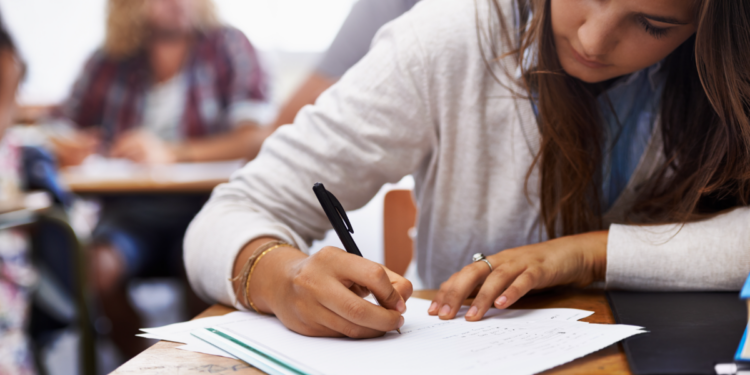Estudante concentrada realizando prova em sala de aula.