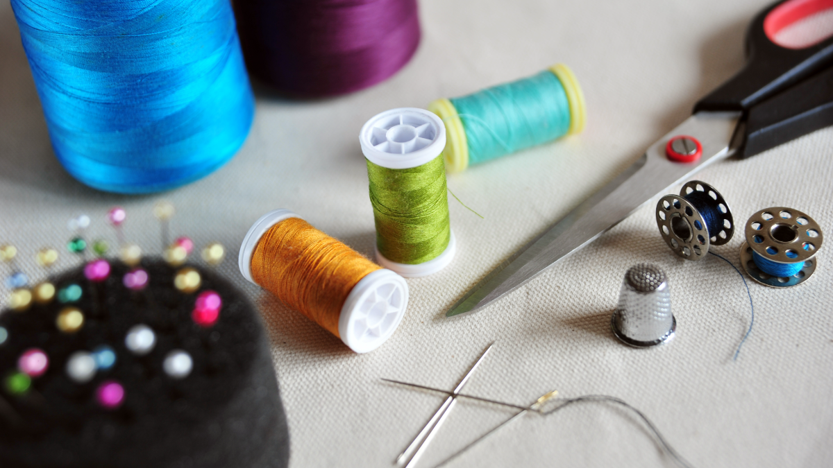 Kit de costura com linhas coloridas, alfinetes e tesoura em foco artesanal.