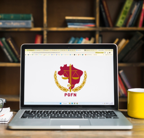 Logo da PGFN exibido em notebook sobre mesa com caneca amarela.