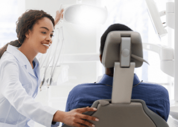 Dentista conversa com paciente em consultório moderno.