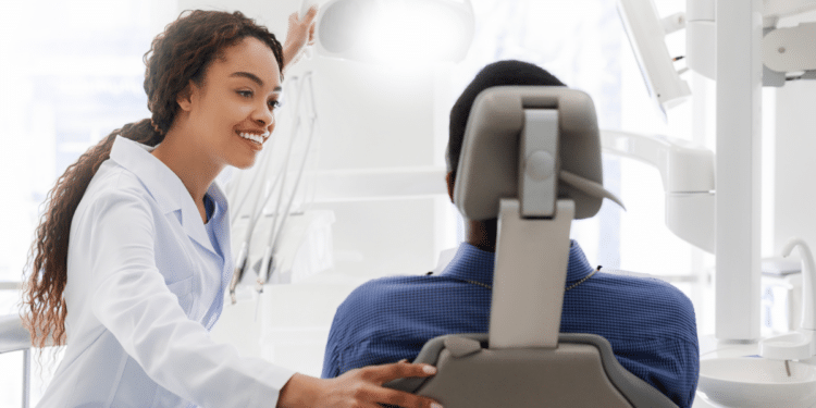 Dentista conversa com paciente em consultório moderno.