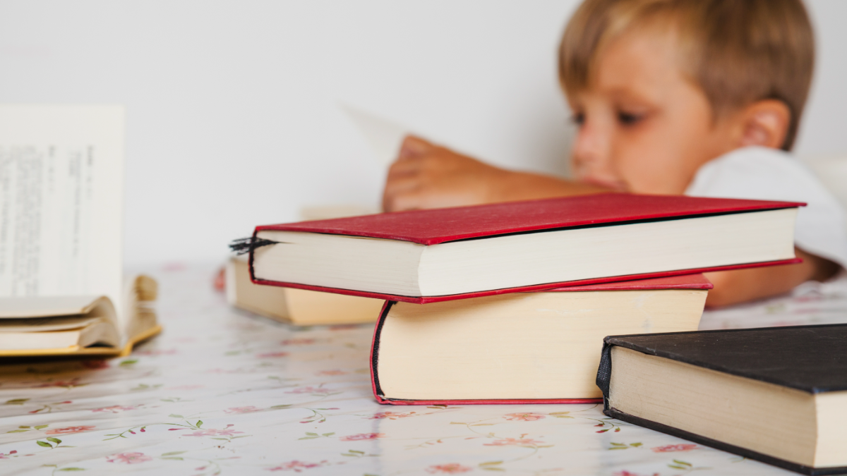 Criança concentrada estudando com vários livros em casa.