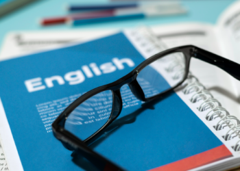 Materiais de estudo de inglês organizados em mesa com óculos.