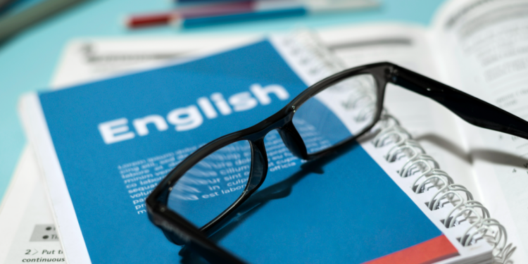 Materiais de estudo de inglês organizados em mesa com óculos.