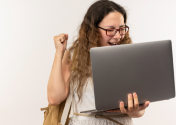 Jovem celebra conquista acadêmica ao receber notícia no notebook.