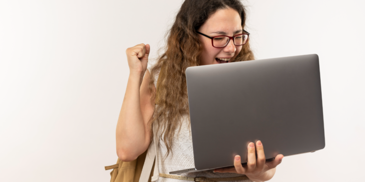 Jovem celebra conquista acadêmica ao receber notícia no notebook.