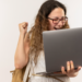 Jovem celebra conquista acadêmica ao receber notícia no notebook.