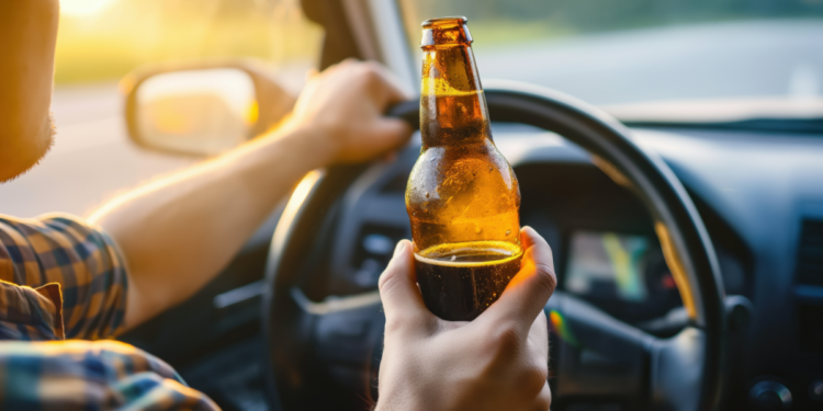 Motorista segurando cerveja enquanto dirige.