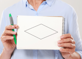 Pessoa exibe caderno com losango desenhado.