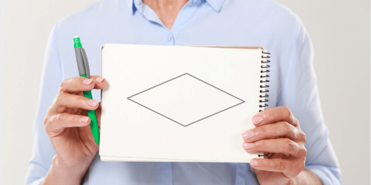 Pessoa exibe caderno com losango desenhado.
