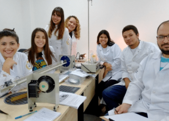 Estudantes de laboratório em aula prática de física com equipamentos.