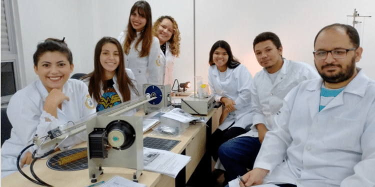 Estudantes de laboratório em aula prática de física com equipamentos.