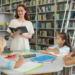 Professora lendo para crianças em biblioteca escolar rodeada de livros.