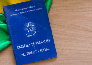 Carteira de Trabalho brasileira sobre mesa com bandeira do Brasil.