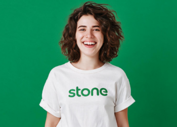 Jovem sorridente com camiseta da Stone em fundo verde.