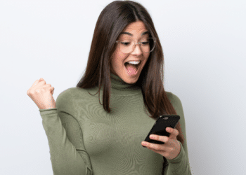 Jovem comemorando novidade no celular com expressão de surpresa.