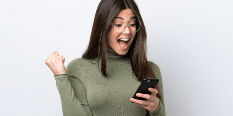 Jovem comemorando novidade no celular com expressão de surpresa.