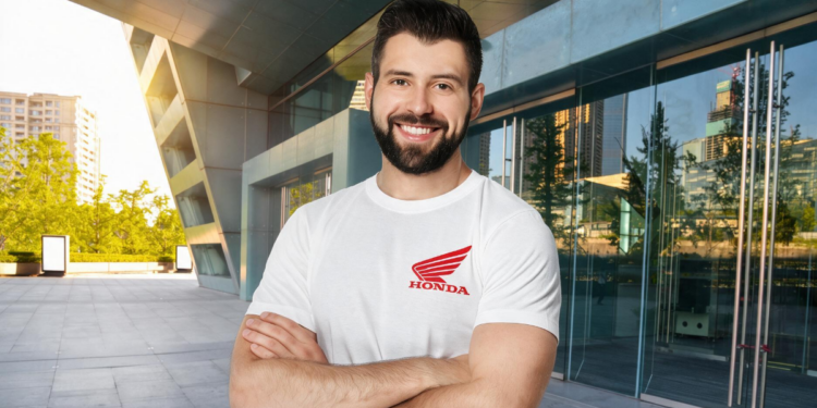 Funcionário com camiseta Honda sorri em frente a prédio comercial moderno.