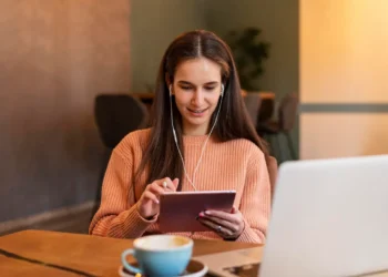 Mulher estudando online com tablet e computador para participar de curso de formação cultural.